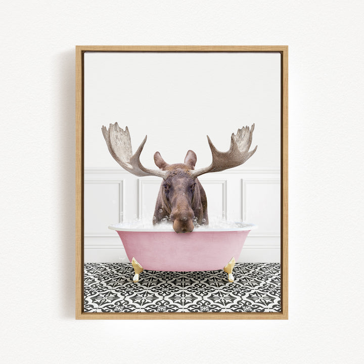 A moose with large antlers is sitting in a pink bathtub filled with water, creating a whimsical and humorous scene.
