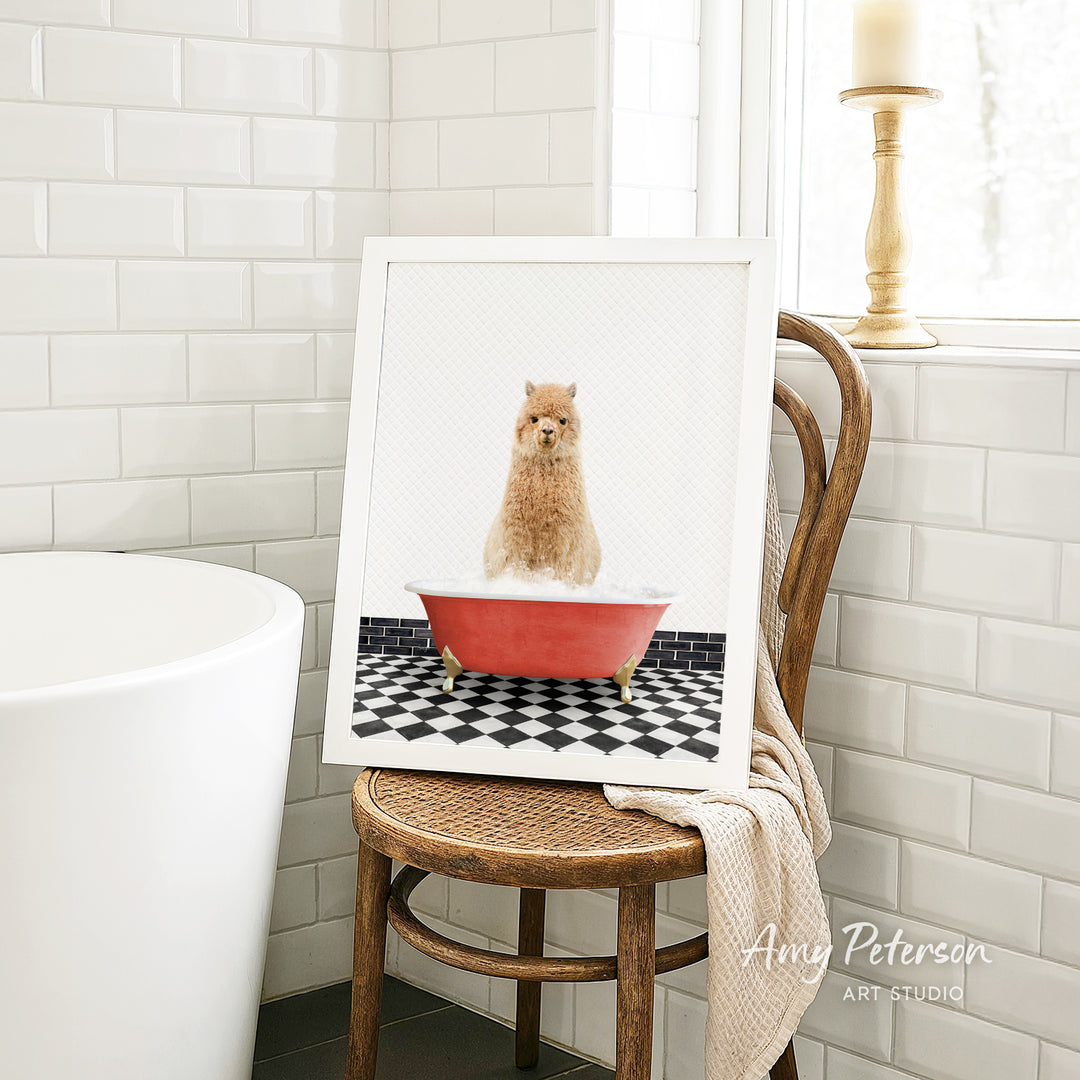 A framed image of a small dog sitting in a red bathtub, surrounded by a black and white checkered floor, is displayed on a wooden chair in a bathroom setting.