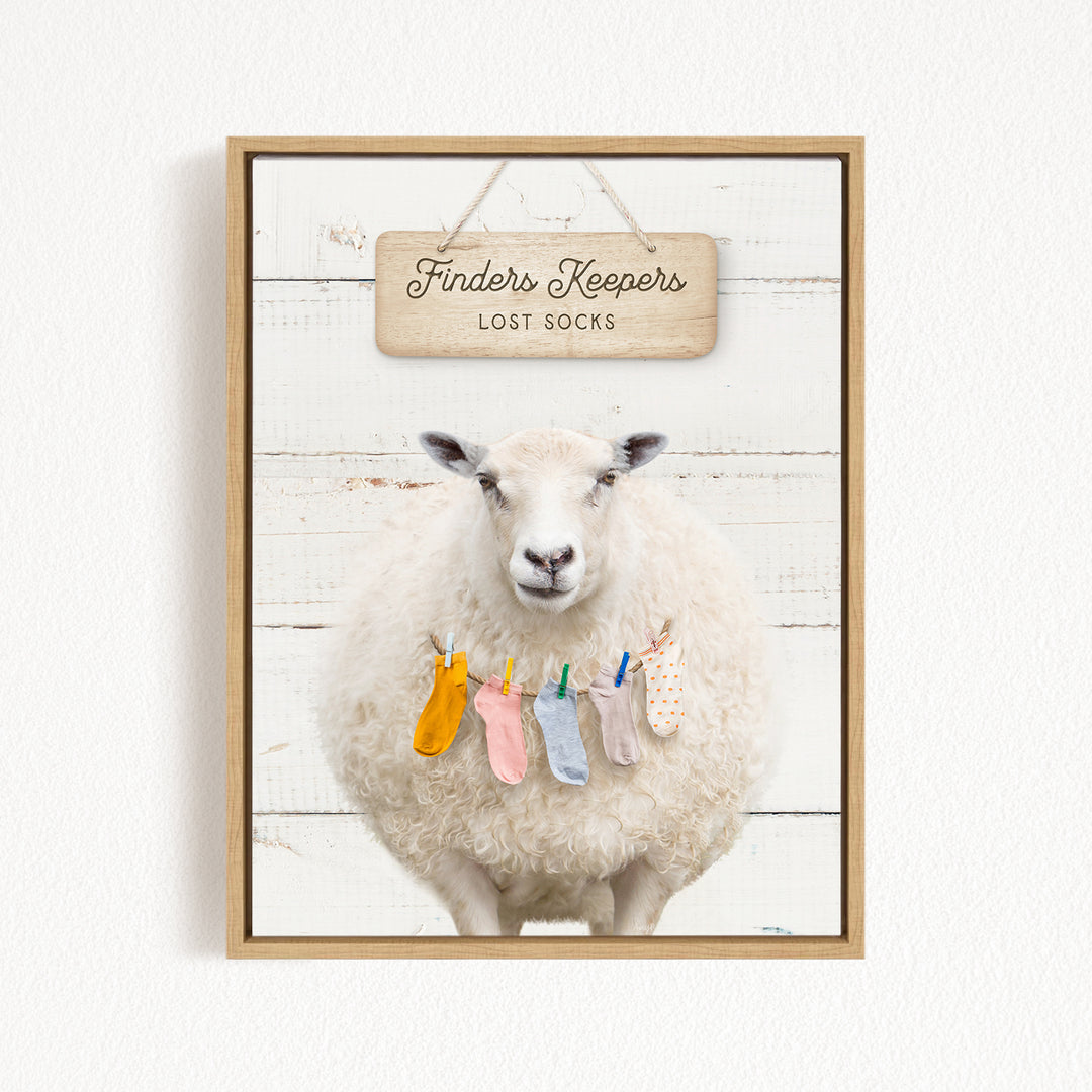 A white sheep with colorful socks hanging on a clothesline, with a wooden sign above that says "Finders Keepers Lost Socks".