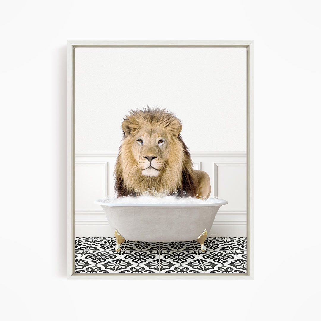 A lion sitting in a white bathtub filled with bubbles, looking directly at the camera.