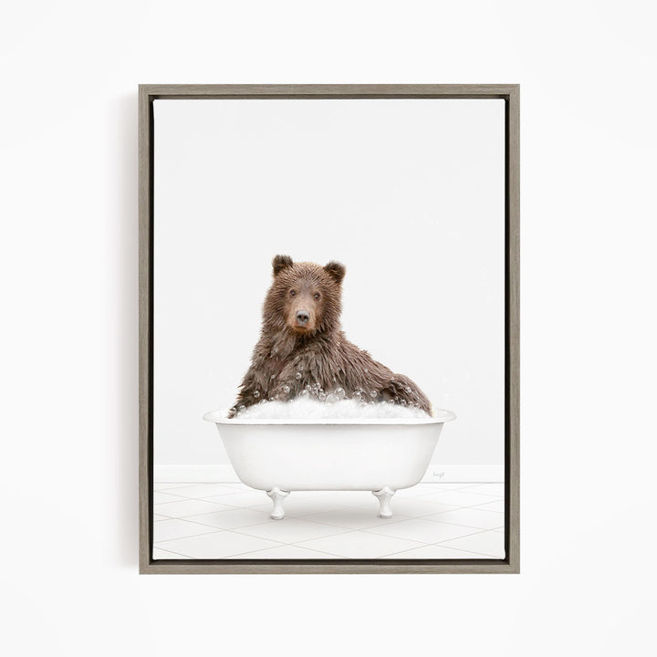 A brown bear sitting in a white bathtub filled with bubbles, looking directly at the camera.