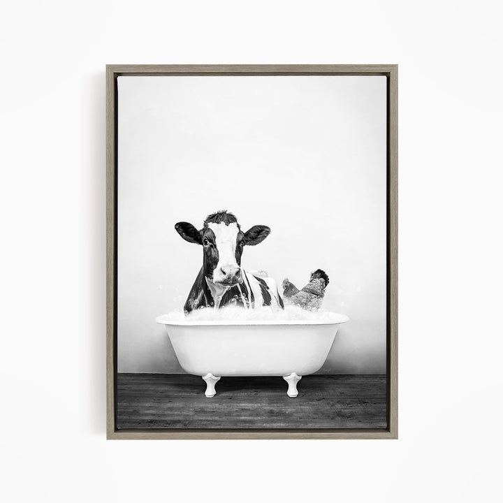 A black and white image of a cow sitting in a bathtub, with a chicken standing nearby.
