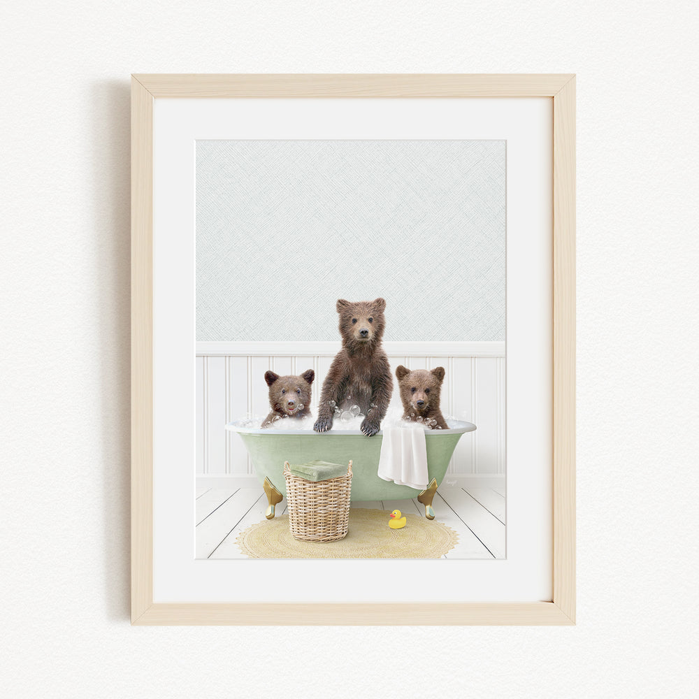 A framed image depicting three bears sitting in a green bathtub, with a yellow rubber duck floating in the water.