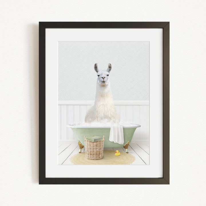 A white llama sitting in a green bathtub filled with bubbles, surrounded by a basket of bath toys and a yellow rubber duck.