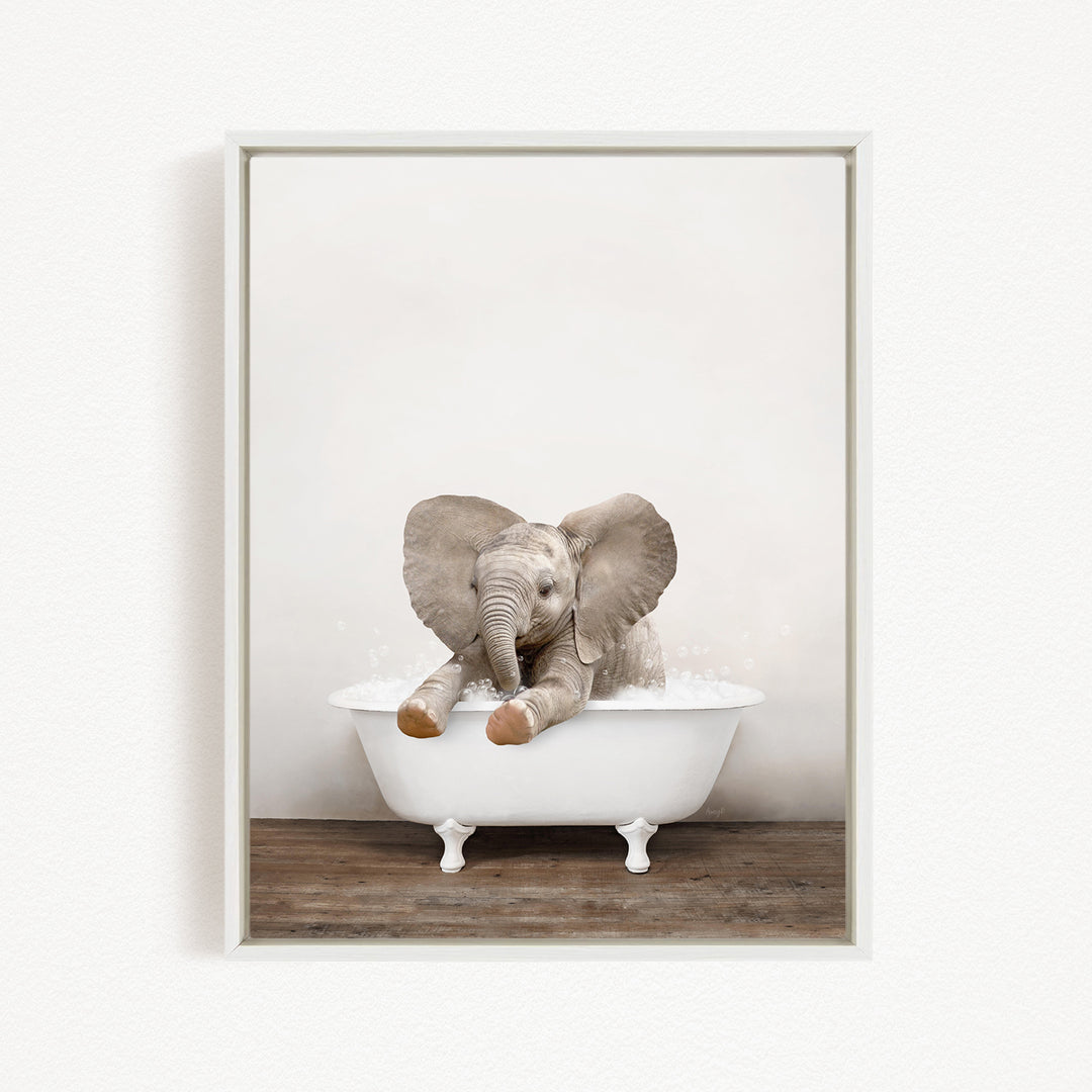 A baby elephant sitting in a white bathtub filled with water, with its trunk raised and ears spread out.