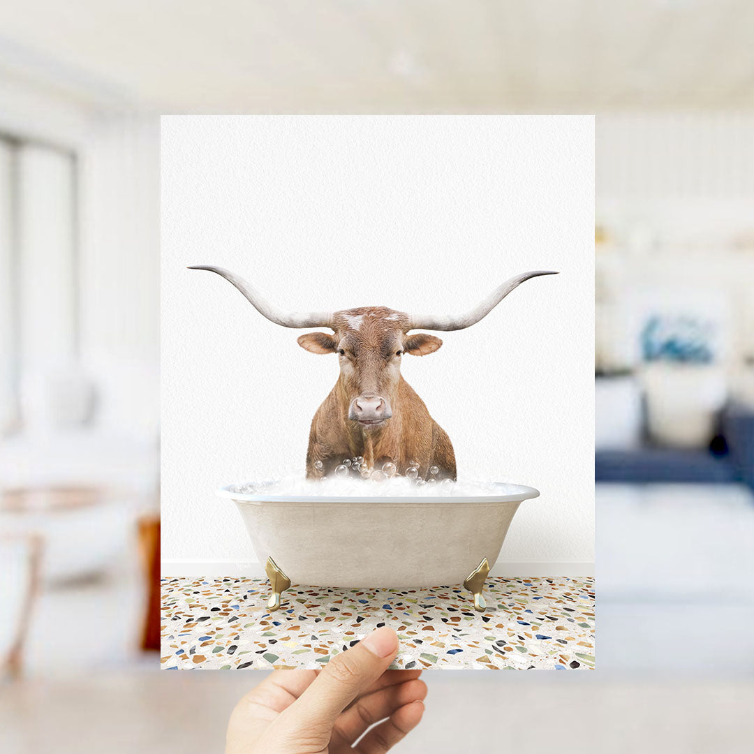 A brown bull with long horns is standing in a white bathtub filled with water, creating a whimsical and humorous scene.