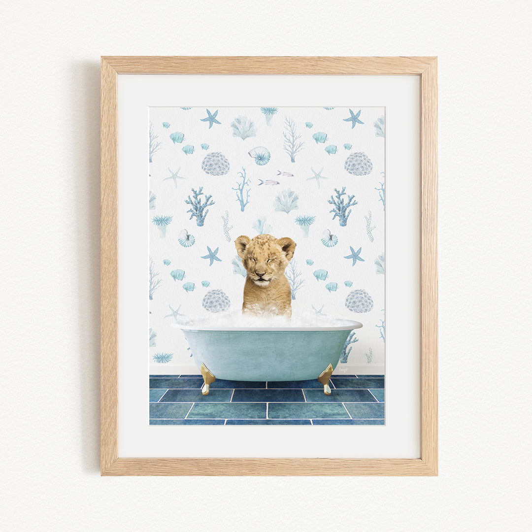 A young lion cub sitting in a bathtub filled with water, surrounded by blue and white seashells and starfish.