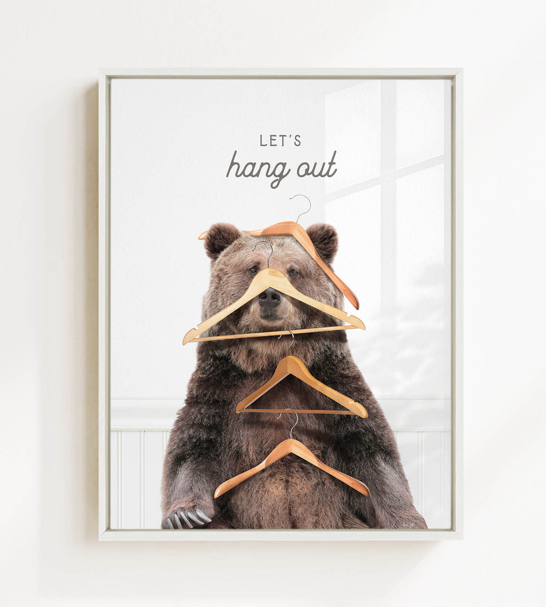 A framed image of a bear sitting on a shelf with multiple wooden hangers hanging from its head and neck.