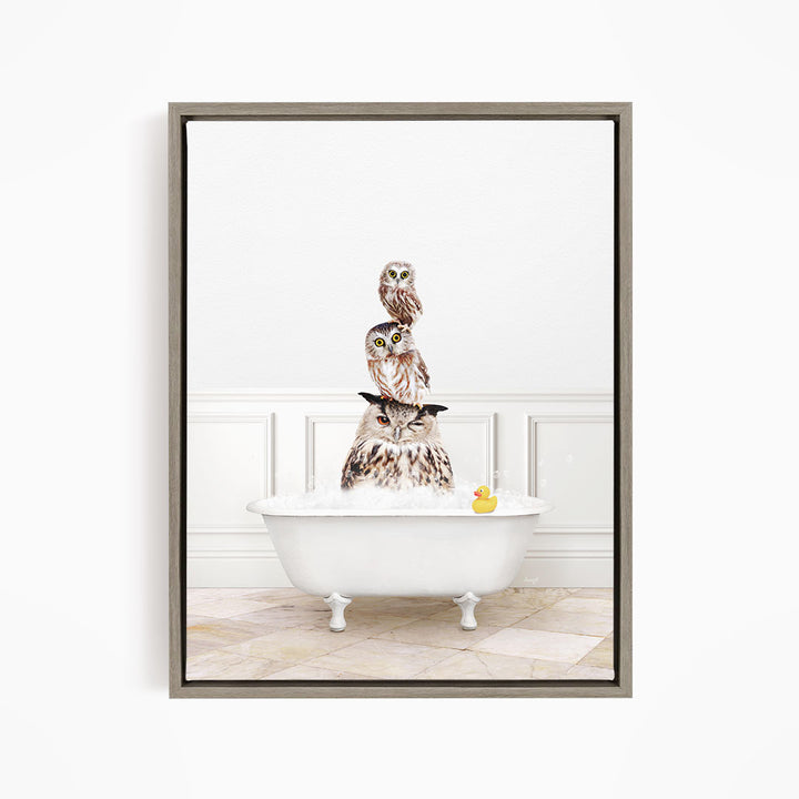 A framed image depicting three owls sitting in a white bathtub, with a rubber duck floating in the water.