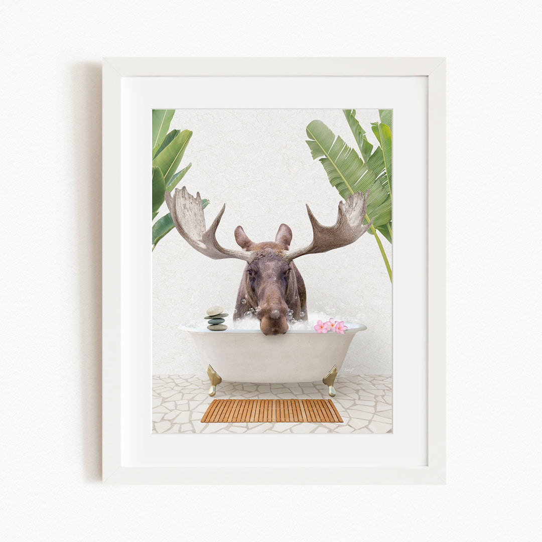 A moose with large antlers is sitting in a white bathtub filled with water, surrounded by tropical plants and flowers.