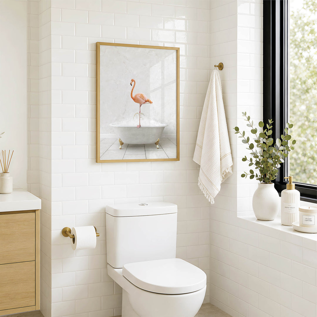 A bathroom with a white toilet, a framed picture of a pink flamingo in a bathtub, and a window with greenery on the sill.
