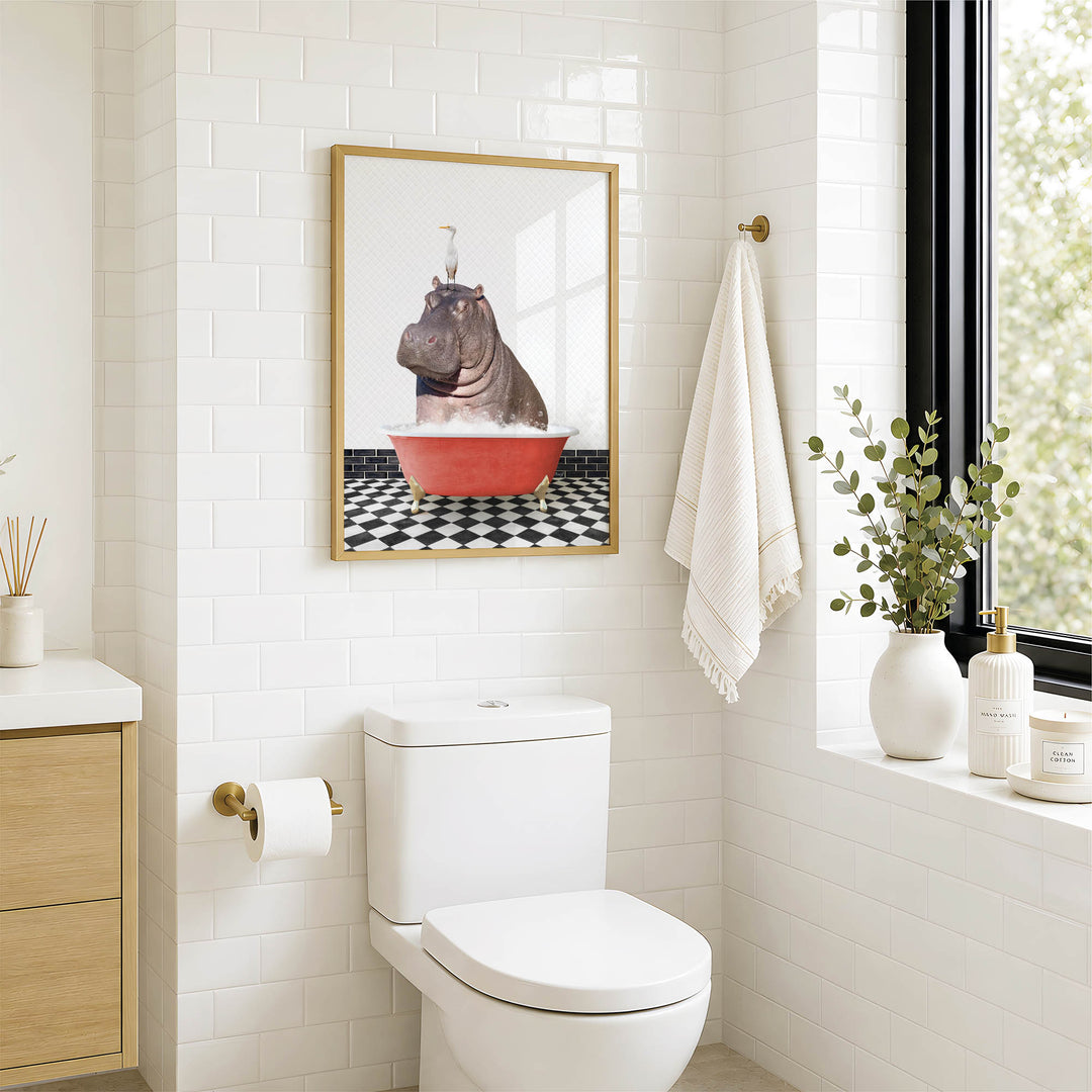 A bathroom with a white toilet, a framed picture of a hippopotamus sitting in a bathtub, and a towel hanging on the wall.