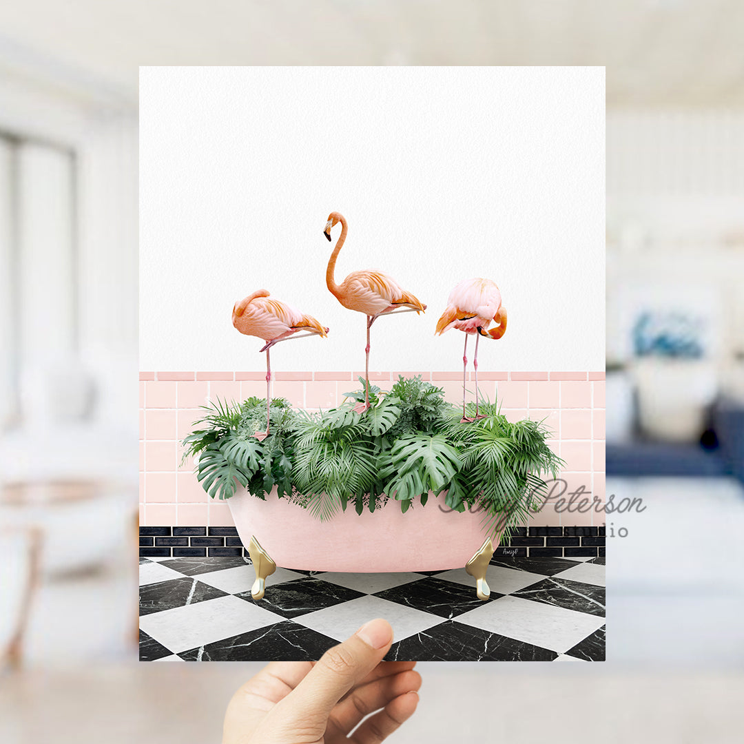 a hand holding a card with three flamingos in a bathtub