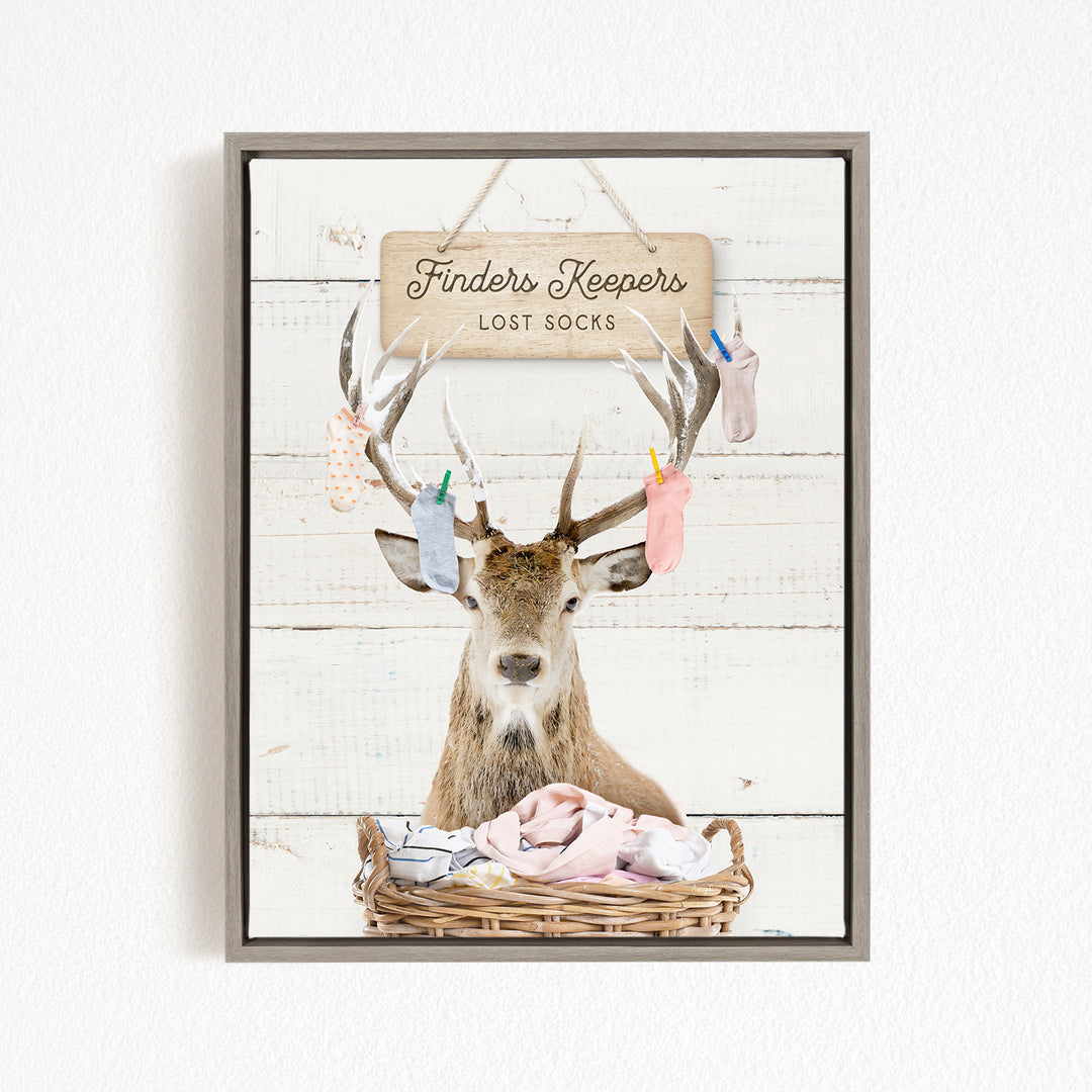 A deer with antlers is sitting in a basket filled with socks, with a sign above that says "Finders Keepers Lost Socks".