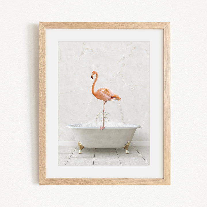A framed image of a flamingo standing on the edge of a white bathtub filled with water.