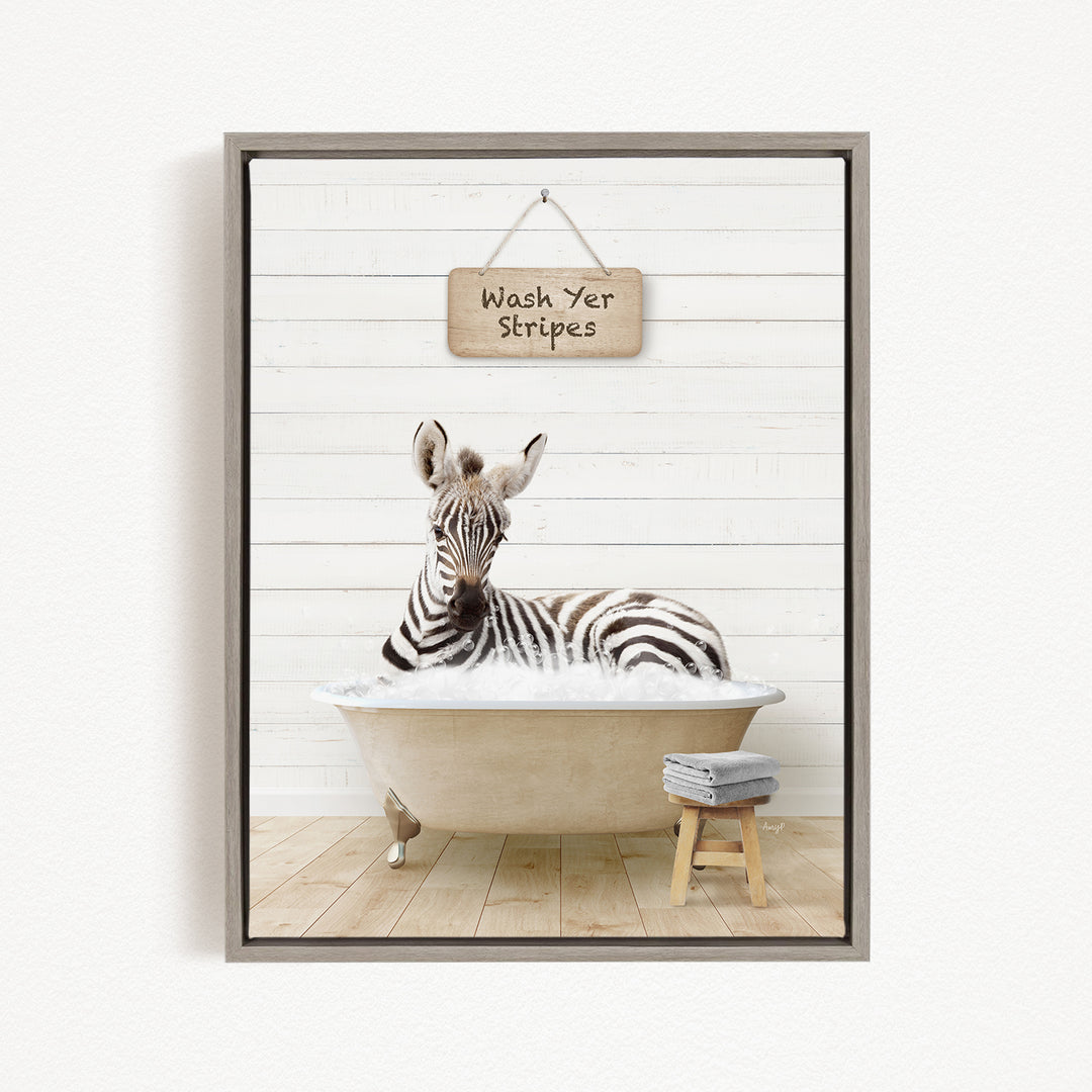 A zebra is sitting in a bathtub, with a sign above it that says "Wash Yer Stripes".