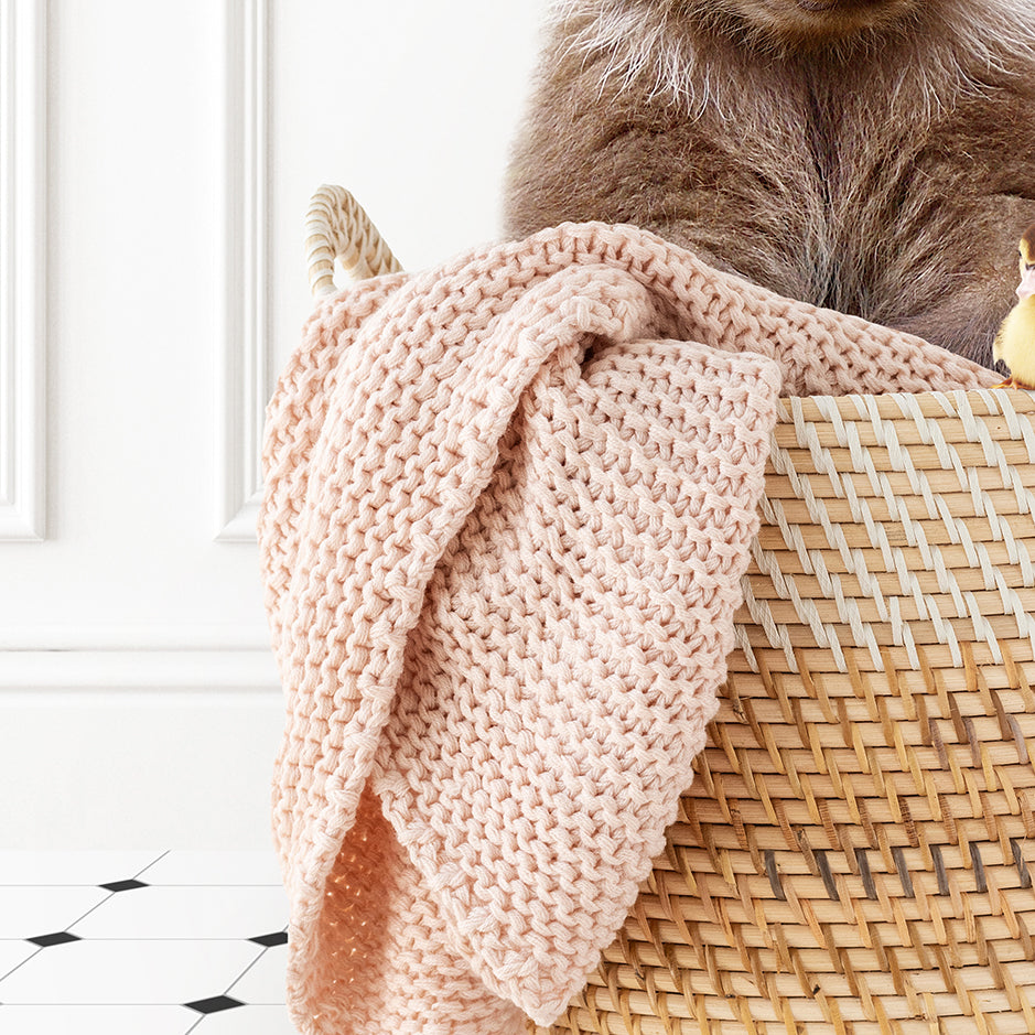 a cat sitting on top of a basket with a blanket