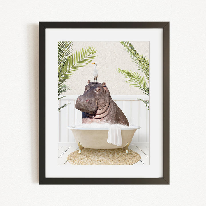 A framed image depicting a hippopotamus sitting in a bathtub, with a bird perched on its head.