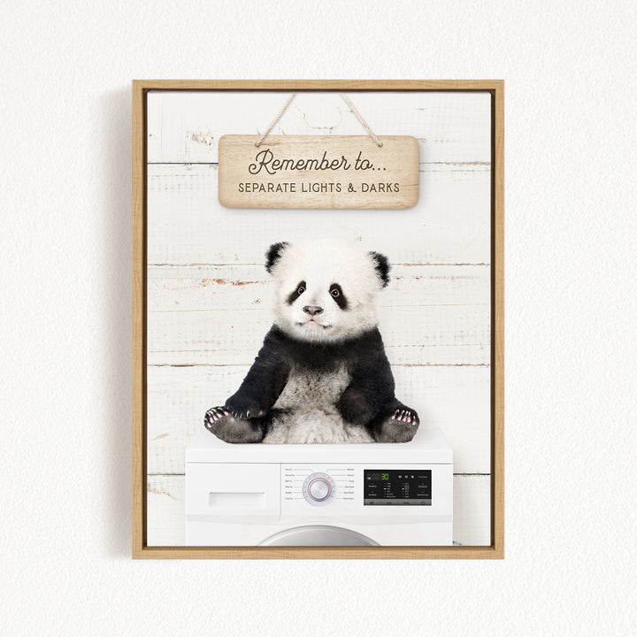 A panda bear sitting on top of a white washing machine, with a wooden sign above that reads "Remember to separate lights & darks".
