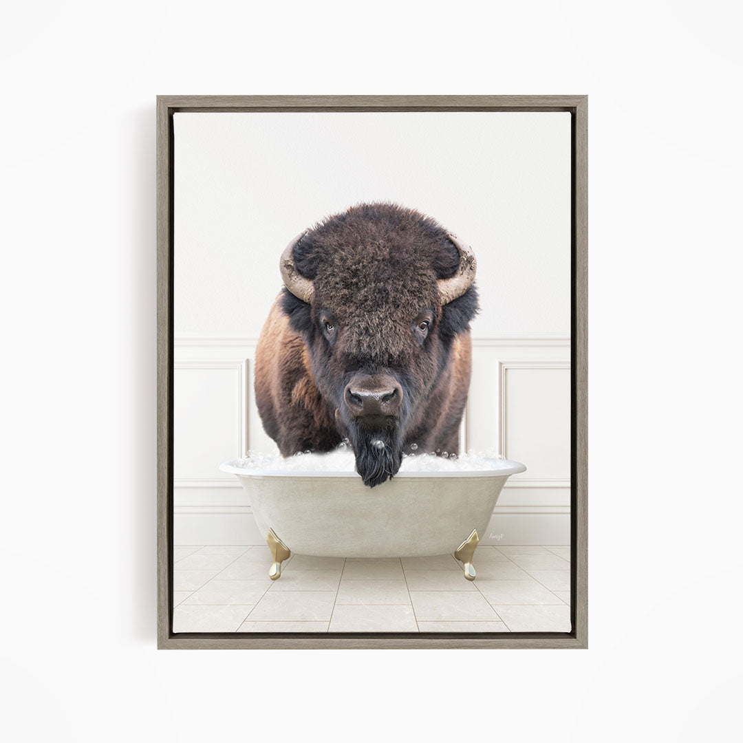 A buffalo with large horns is standing in a white bathtub, appearing to be enjoying a bath.