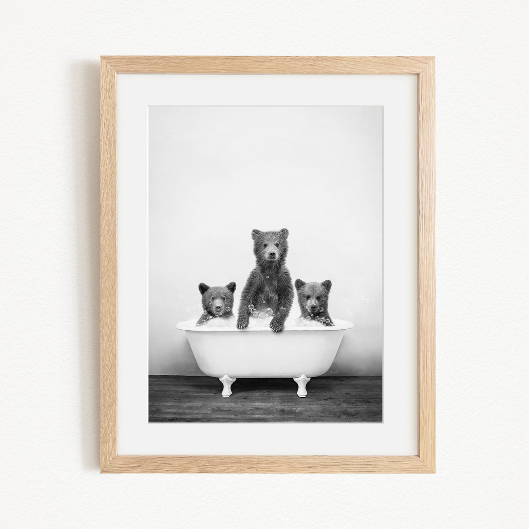 A black and white photograph of three bears sitting in a bathtub, with one bear sitting in the center and the other two bears sitting on either side.