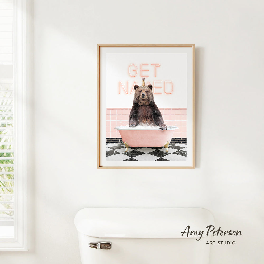 A framed print of a bear sitting in a bathtub with the text "GET NAKED" on it, hanging on a white wall.