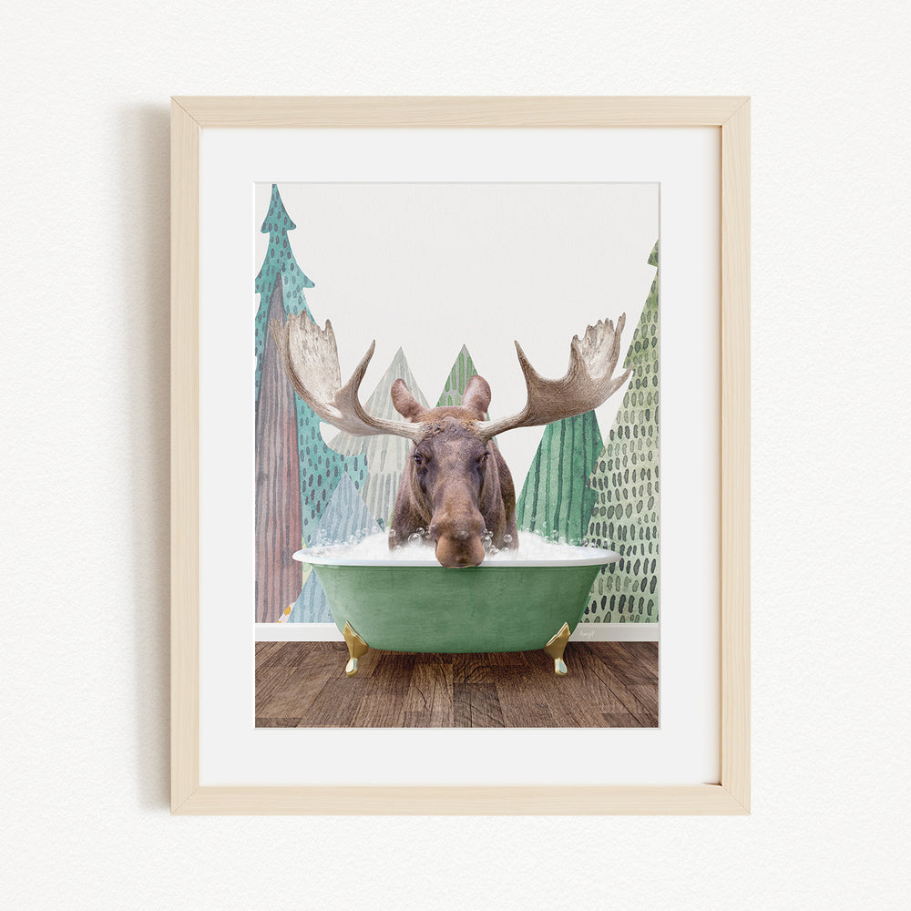 A moose with large antlers is sitting in a green bathtub, surrounded by a forest scene with trees and a snowy landscape.