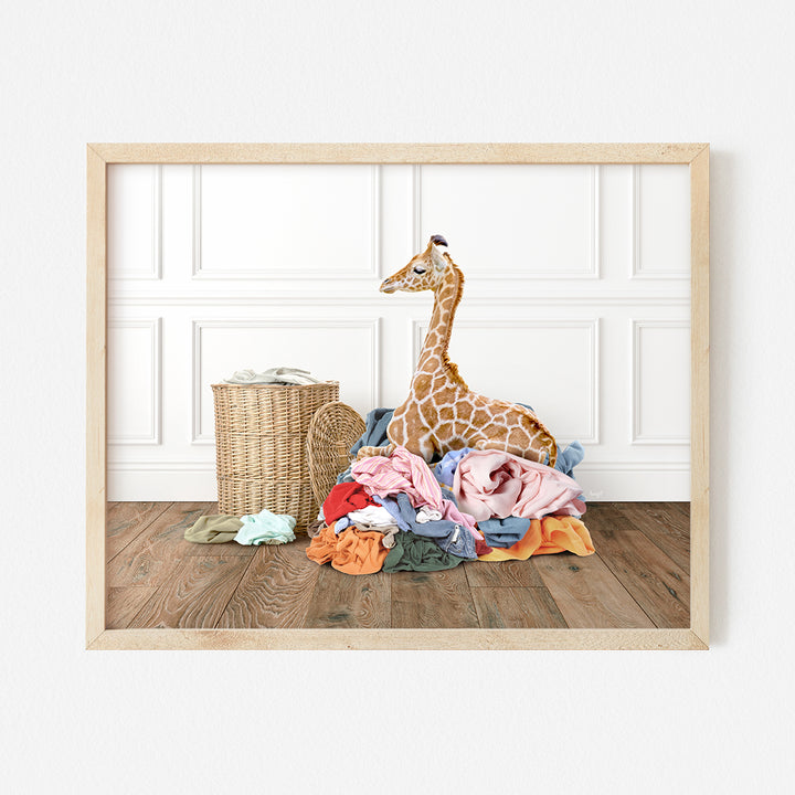 a giraffe sitting on top of a pile of clothes