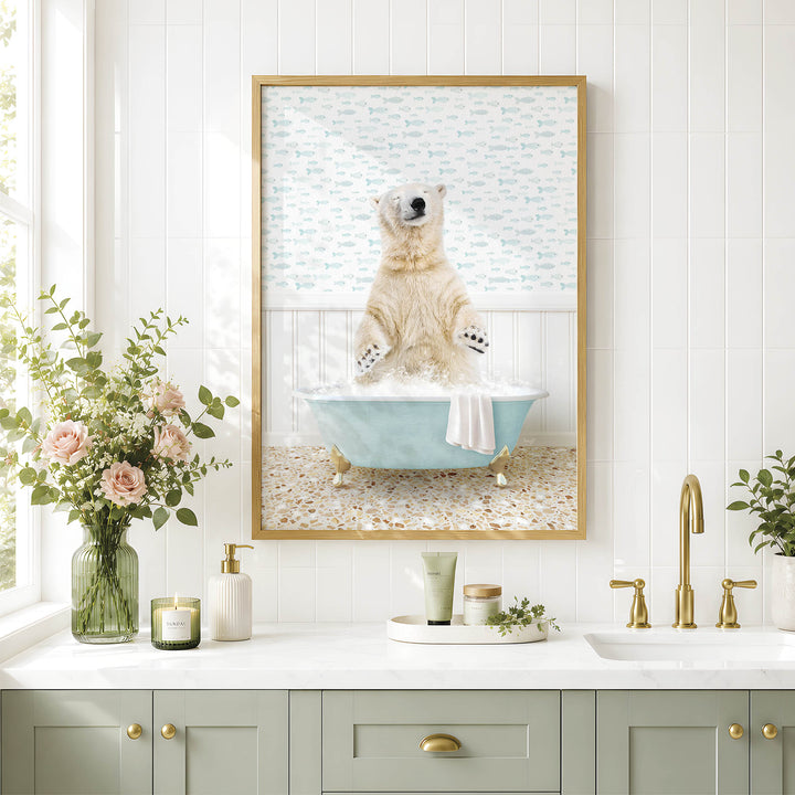 A framed image of a polar bear sitting in a bathtub, surrounded by a blue tub, white towel, and pink flowers, is displayed on a white tiled wall above a bathroom counter with various toiletries and a vase of flowers.