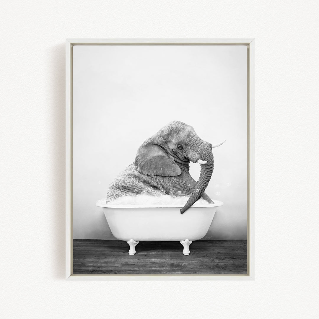 A black and white photograph of an elephant sitting in a bathtub filled with water.