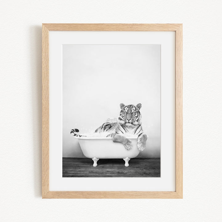 A black and white photograph of a tiger sitting in a bathtub filled with water.