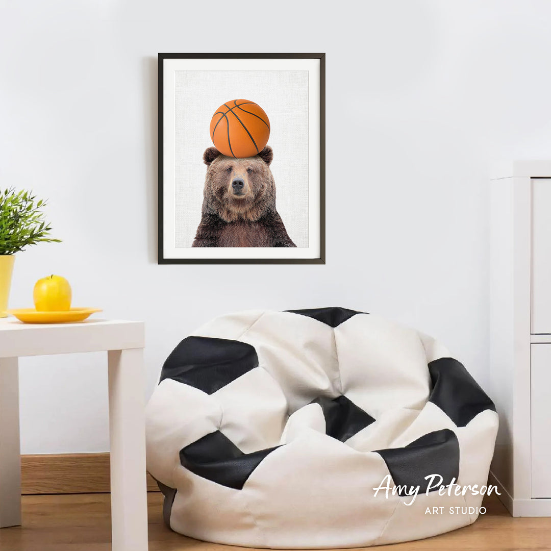a framed picture of a bear with a basketball on its head, hanging on a wall in a room with a white table and a black and white bean bag chair.