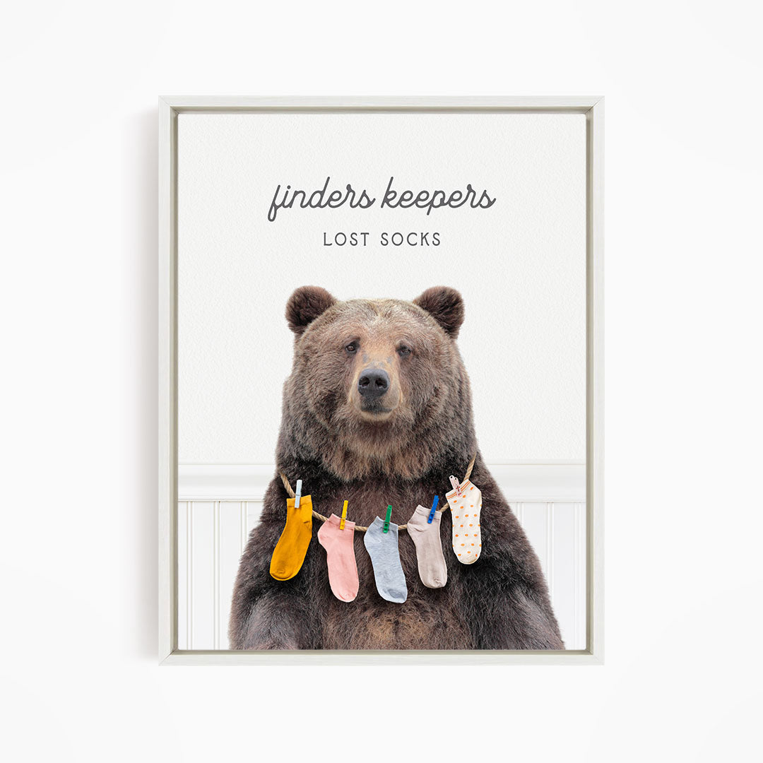 A brown bear wearing a colorful array of socks hanging from clothespins, with the text "finders keepers" and "lost socks" above the bear.