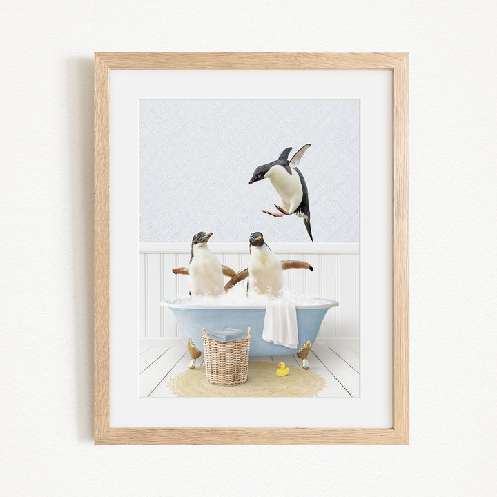 A framed image depicting two penguins sitting in a bathtub, with one penguin flying towards the other.