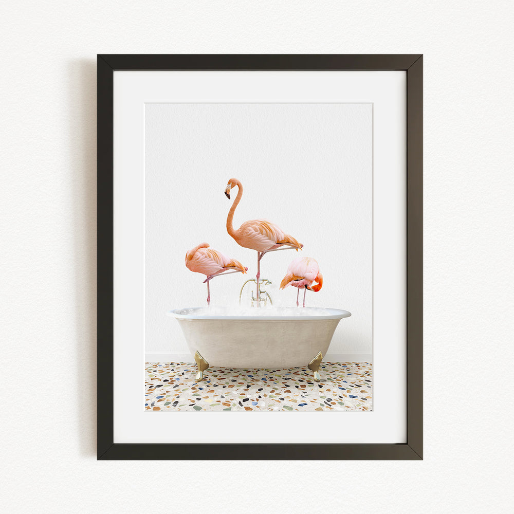 A framed image depicting three flamingos standing in a white bathtub filled with water.