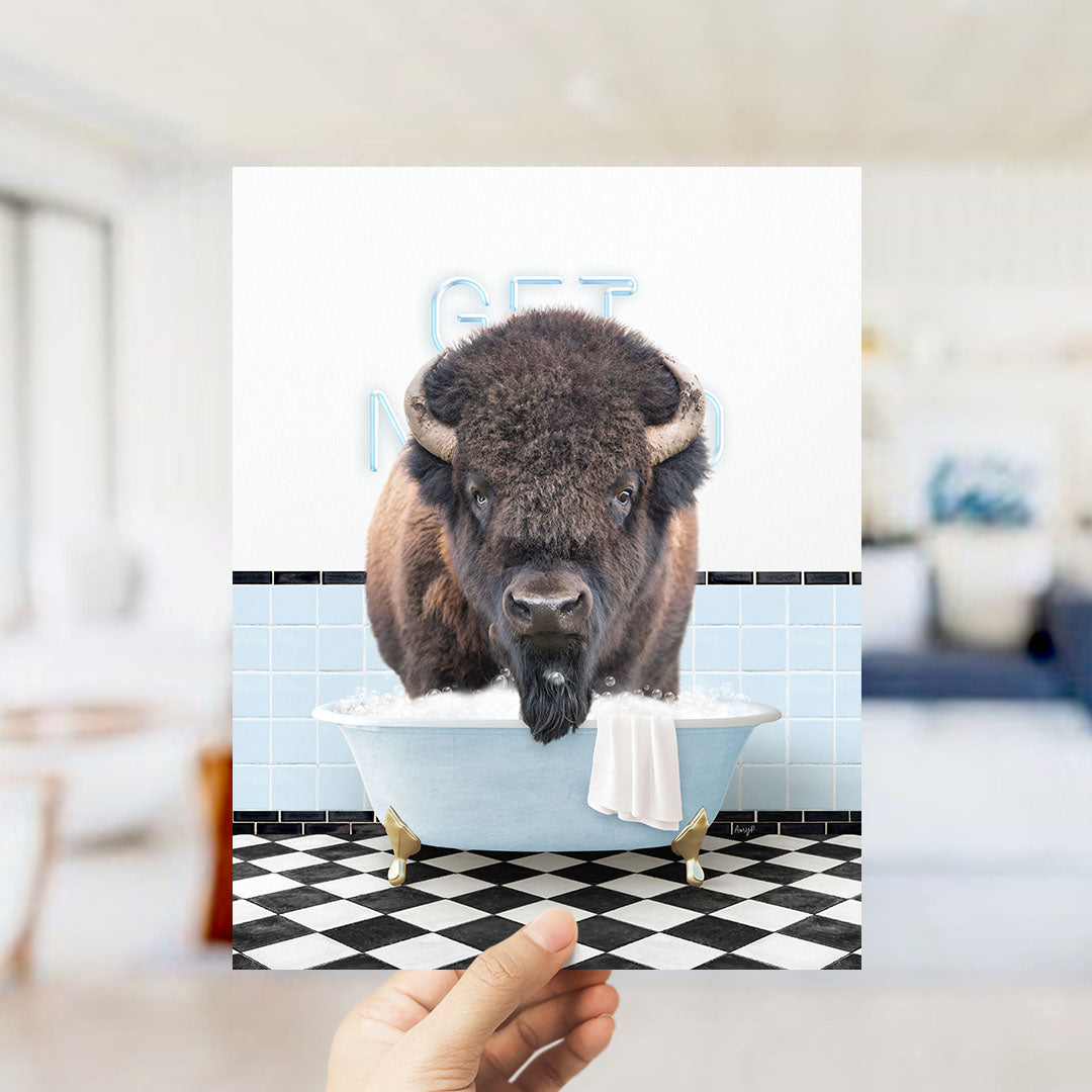 A buffalo is sitting in a bathtub filled with bubbles, with a towel hanging over the side of the tub.