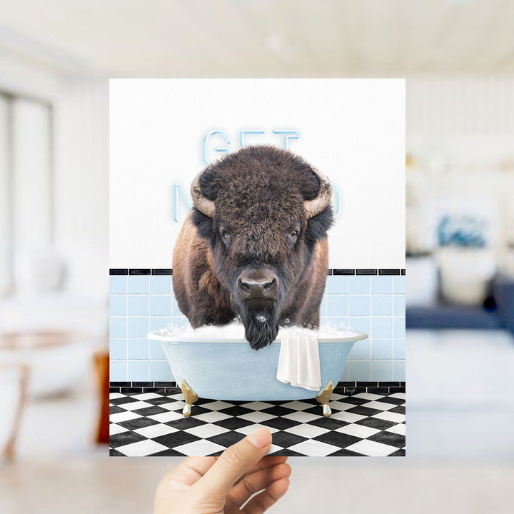 A buffalo is sitting in a bathtub filled with bubbles, with a towel hanging over the side of the tub.