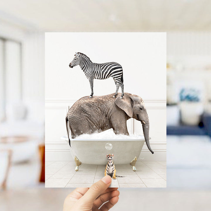 A hand holds up a collage of two images: a zebra standing on an elephant's back in a bathtub, and a small tiger figurine sitting in the tub.