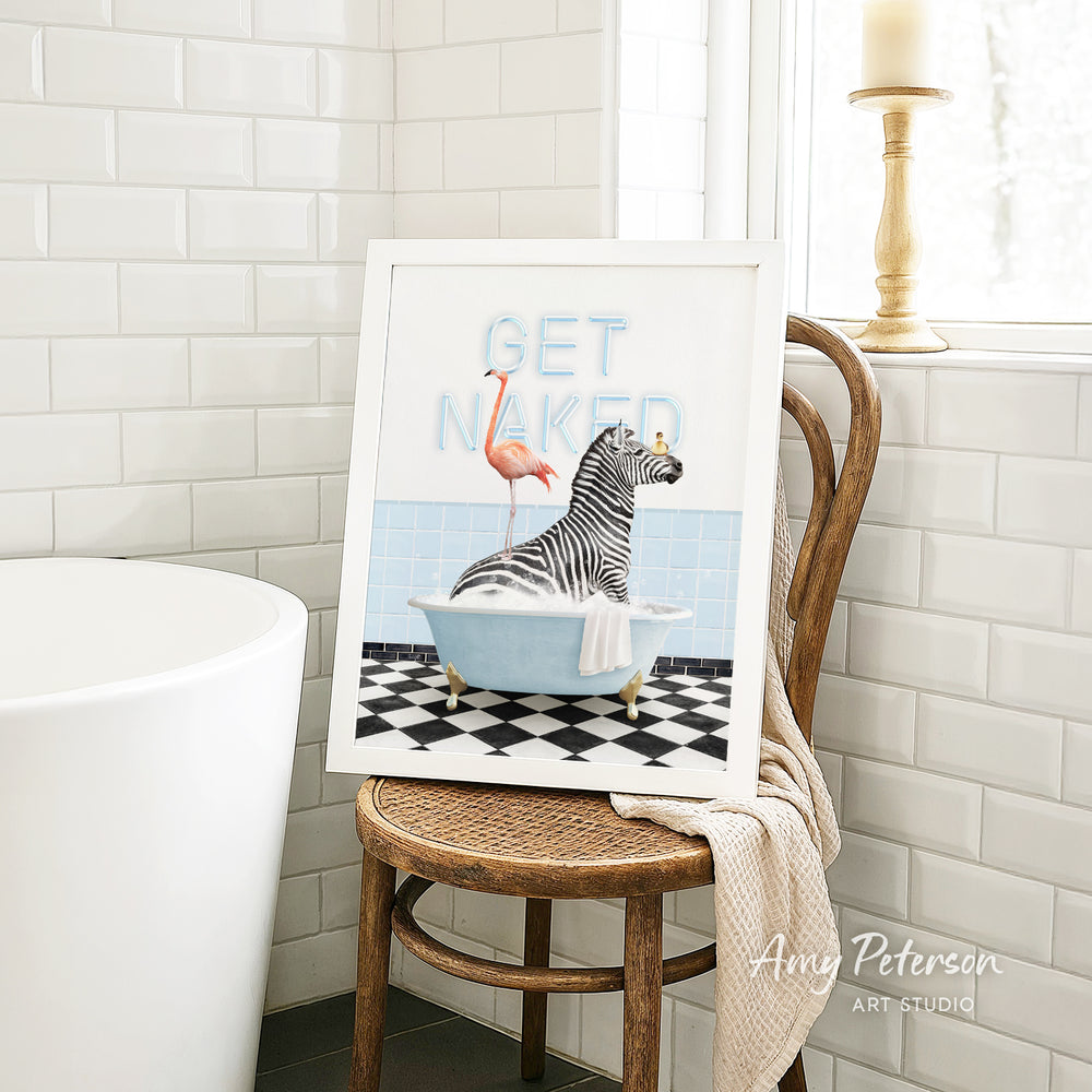 a framed artwork depicting a zebra sitting in a bathtub, with a flamingo perched on its back. The artwork is displayed on a wooden chair in a bathroom setting.