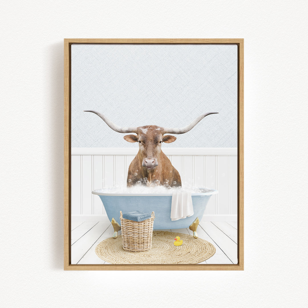 A brown cow with long horns is sitting in a blue bathtub filled with water, surrounded by a basket of toys and a yellow rubber duck.