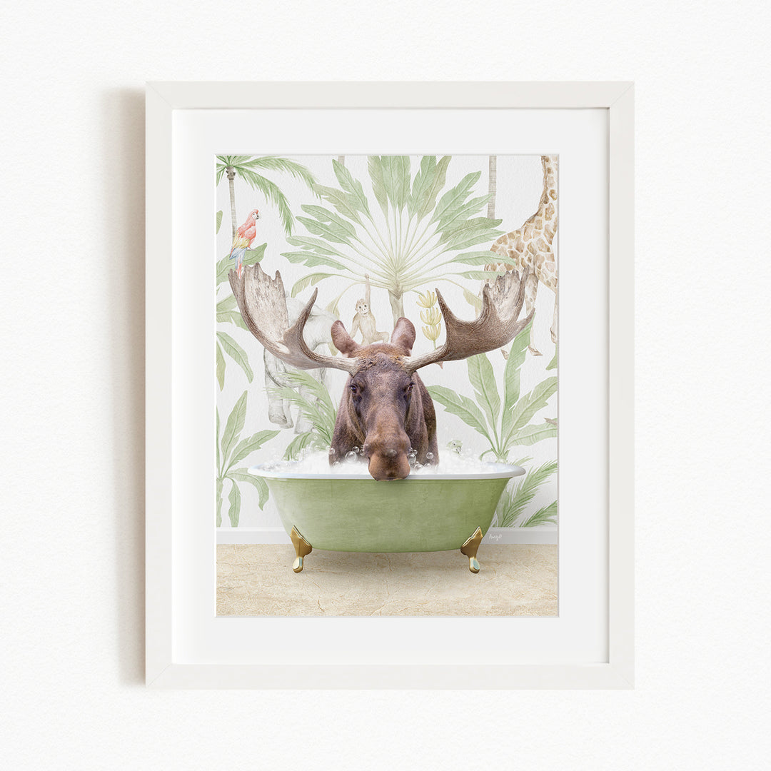 A moose with large antlers is sitting in a green bathtub, surrounded by a tropical wallpaper with palm leaves and a giraffe.