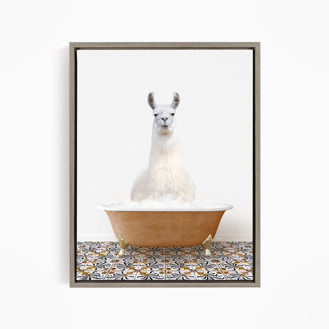 A white llama sitting in a bathtub filled with bubbles, with a patterned tile floor beneath it.