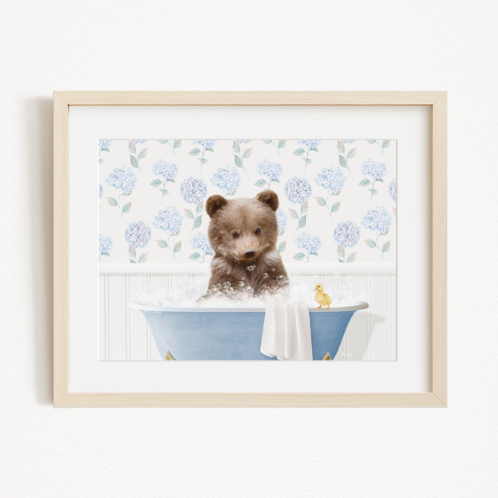 A brown bear sitting in a blue bathtub filled with bubbles, with a yellow rubber duck floating nearby.