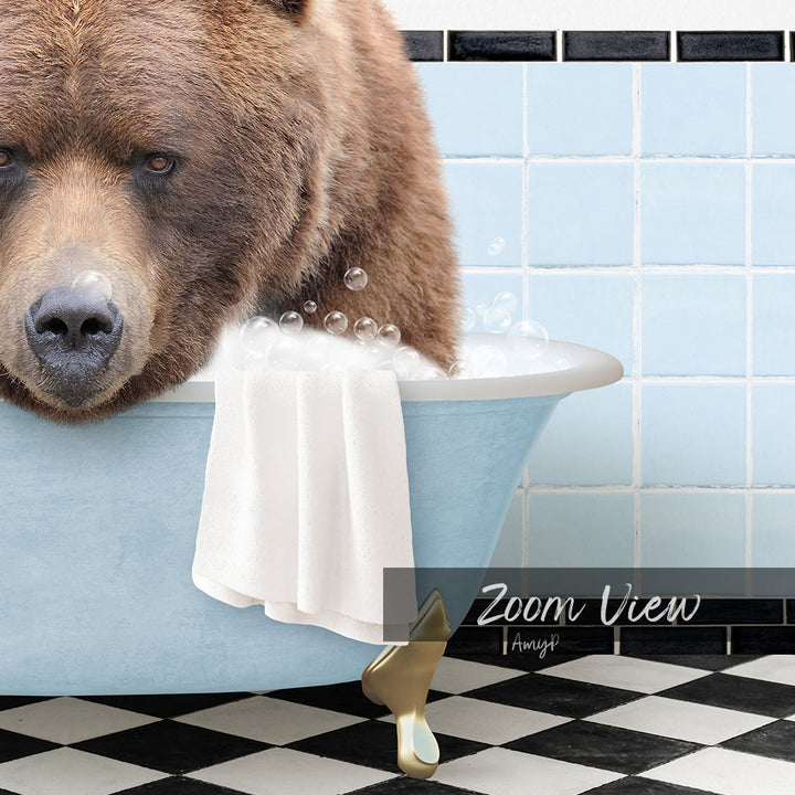 A large brown bear is sitting in a blue bathtub filled with bubbles, with a towel draped over the side of the tub.
