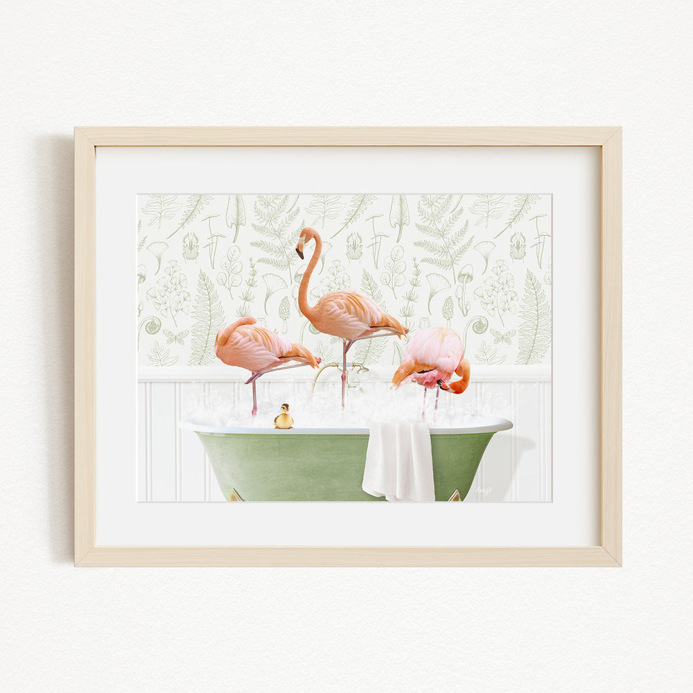 A framed image depicting three pink flamingos standing in a green bathtub filled with water, with a towel draped over the side.