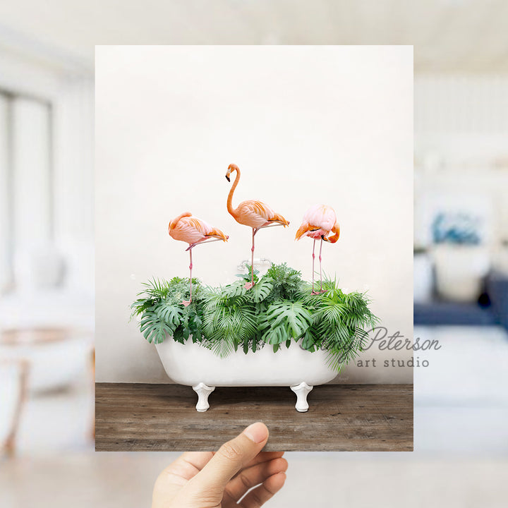 a hand holding a card with three flamingos in a bathtub