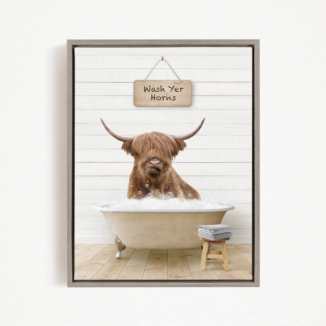 A brown Highland cow is sitting in a bathtub filled with water, with a sign above it that says "Wash Yer Horns".