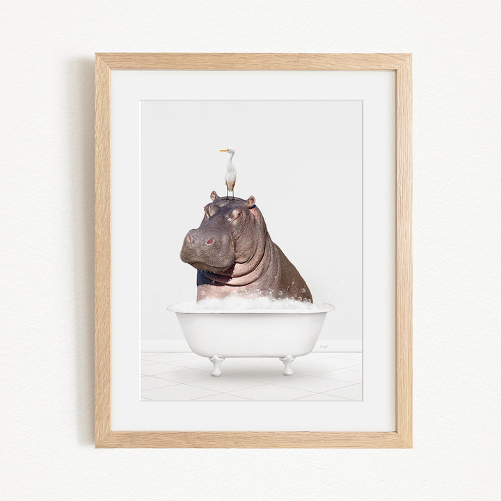 A framed image depicting a large hippopotamus sitting in a bathtub, with a seagull perched on its head.