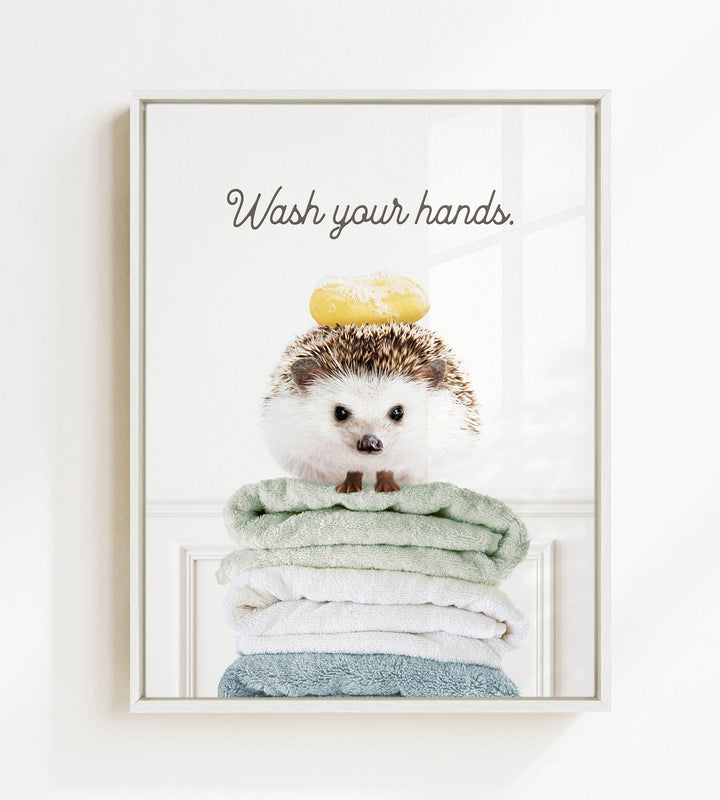 A cute hedgehog sitting on a stack of colorful towels, with the text "Wash your hands" written above it.