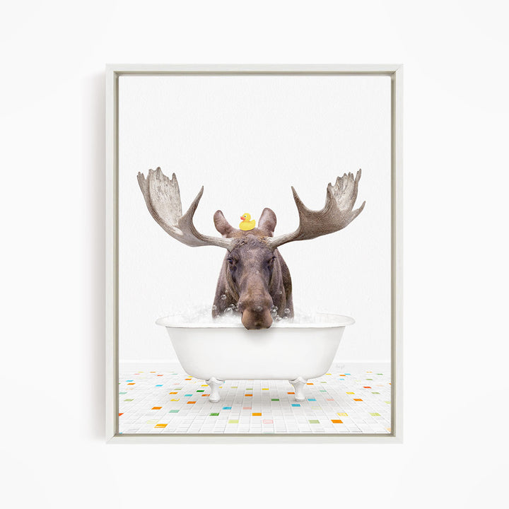 A moose with large antlers is sitting in a white bathtub, with a rubber duck perched on its head.